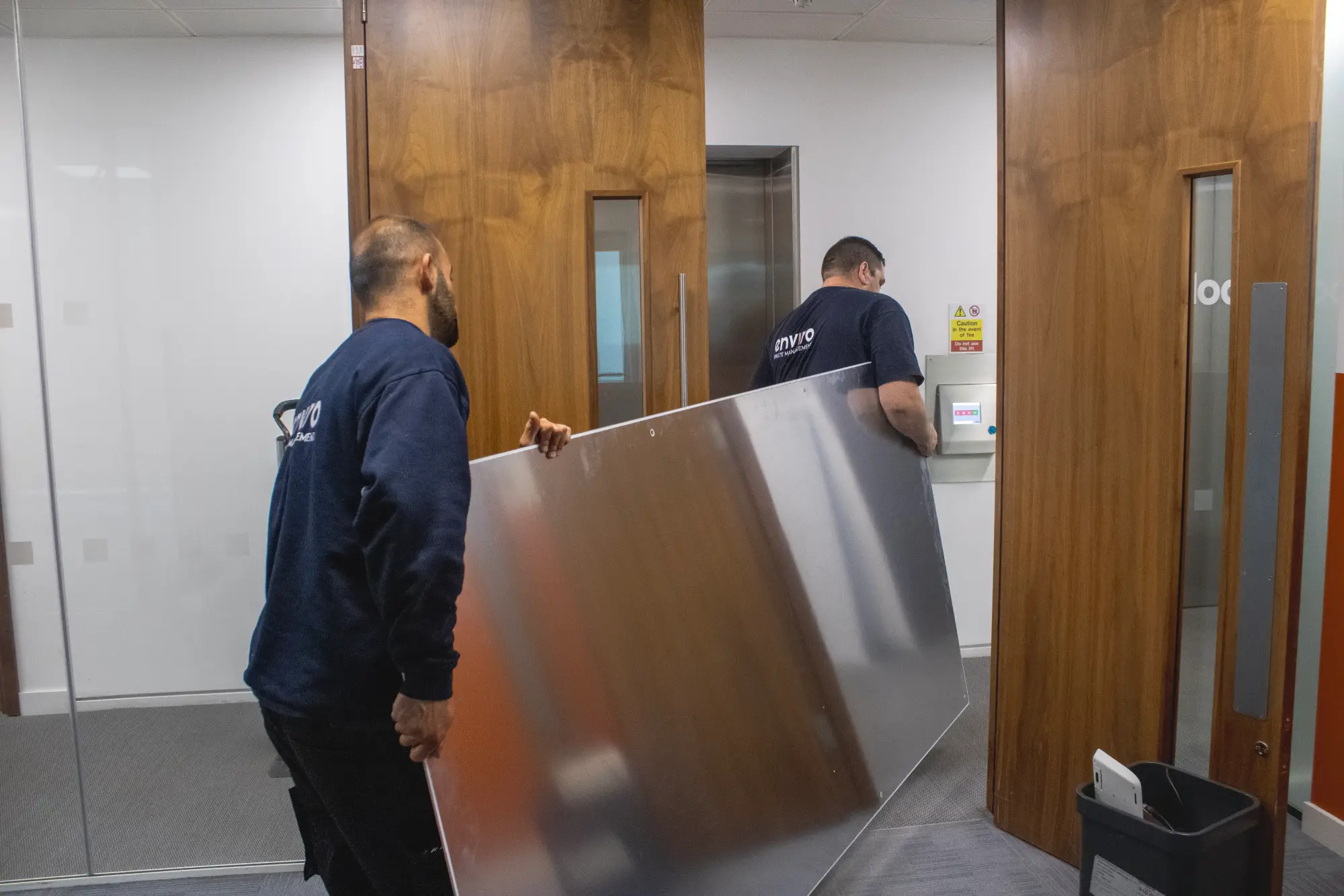 5 Steps for an Accurate Office Clearance Quote 2 Enviro Waste Management team carrying large office furniture through a doorway during an office clearance